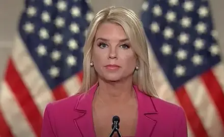 Image of Pam Bondi speaking at RNC, standing at microphone in bright pink suit with American flags visible behind her. 