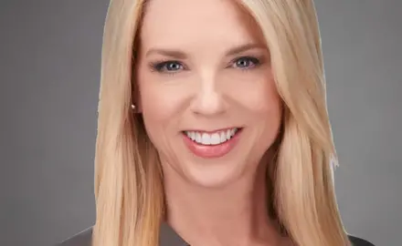 Pam Bondi headshot; white women with long blonde hair below shoulders smiles into the camera. 