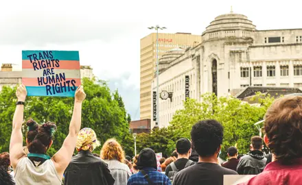 protestors holding a sign that reads "trans rights are human rights"