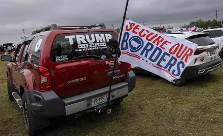 Truck with a Trump window decal and a flag that reads "secure our borders"