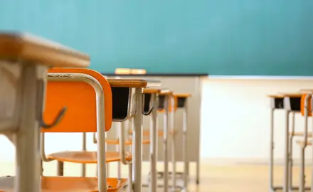 An empty classroom with desks and a chalkboard.