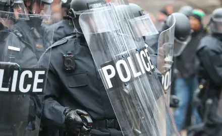 A group of police in riot gear with riot shields.