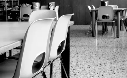 A black and white image of school tables and chairs.