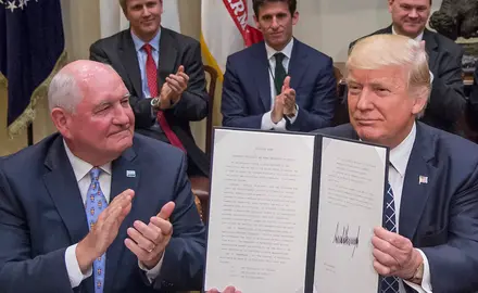 Agriculture Secretary Sonny Perdue with Trump holding up a signed executive order.