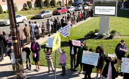 A group of people outside a church holding signs