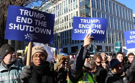 A group of people holding signs that say "Trump: End the shutdown"