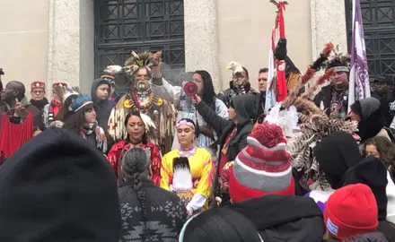 A group of indigenous people surrounded by onlookers