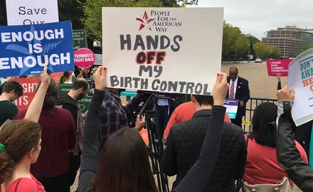 People hold signs that say "Enough is enough," "Hands off my birth control" and "Don't take away our health care ever"