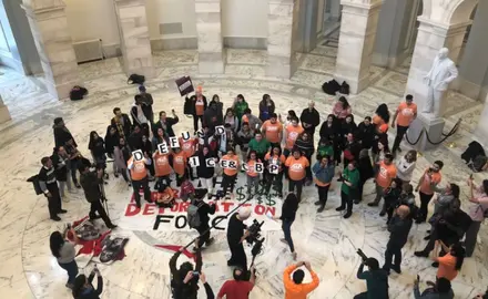 A group of protesters hold signs that say "Defund ICE and CBP"