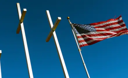 The American flag waves next to three large crosses