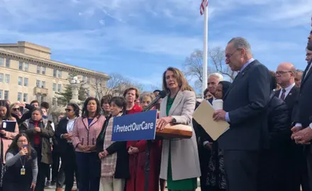 Nancy Pelosi speaks at a podium in front of a group of people.