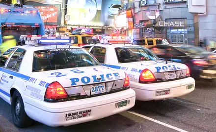 Two police cars drive side-by-side down a busy street