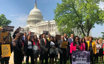 Activists stand outside the U.S. Capitol Building and hold signs that support Brown v. Board