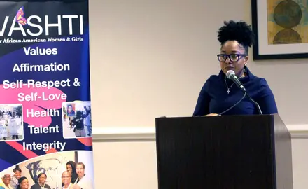 Lauren Wilson speaks from behind a podium at the 2019 spring VASHTI Convocation