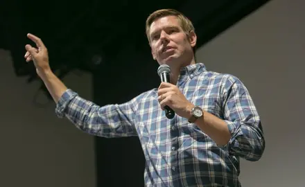 Democratic presidential candidate Eric Swalwell wearing a blue plaid shirt and answering a question