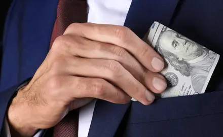 A man puts a $100 bill into his jacket pocket