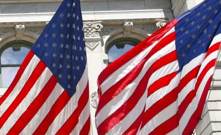 picture of two American flags against a white building