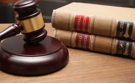 Judge's gavel in a courtroom, stack of law books.