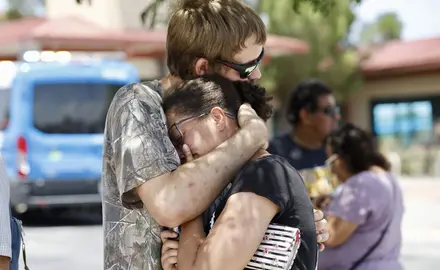 A man hugs a woman tight to his chest.