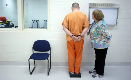 A nurse measures a prisoner's weight