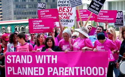 Protesters in Chicago wearing pink and carrying signs that say "I stand with Planned Parenthood."