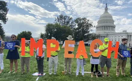 A line of activists in from of the U.S. Capitol Building holding the letters of the word "IMPEACH"
