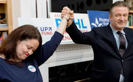 Actor Alec Baldwin holds Amanda Pohl's hand at a campaign event.