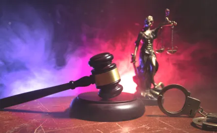 An image of handcuffs, a gavel, and Lady Justice.