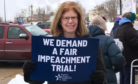 PFAW activist holds a sign outside of Senator Joni Ernst's office in Cedar Rapids