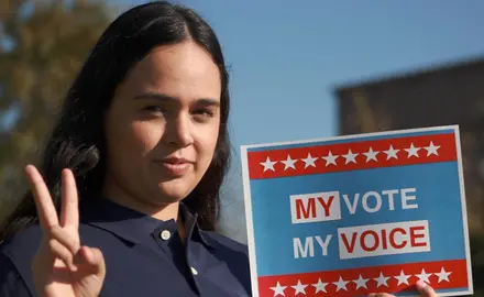 A woman holds a sign that says "My vote, my voice."