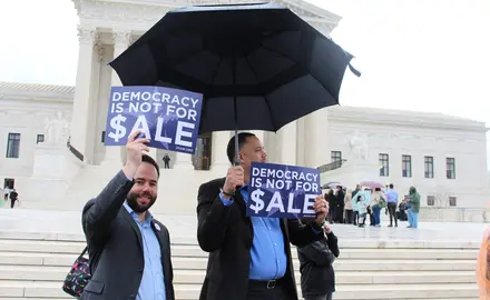 PFAW staff holds signs saying "Democracy Is Not for Sale" in front of the Supreme Court