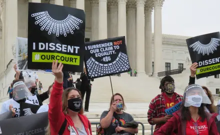 Activists hold signs that read "I Dissent #OurCourt" in front of the Supreme Court.