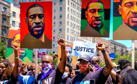 Protesters holding signs featuring George Floyd's image.