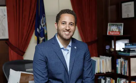 Svante Myrick in a blue jacket posing in an office.