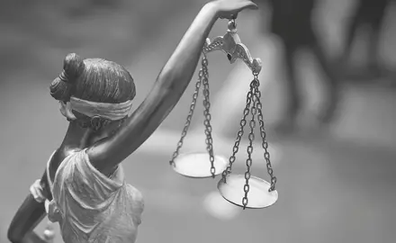 Black and white photograph of a statue of ablindfolded woman holding the scales of justice