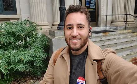 Svante Myrick standing outside a courthouse displaying an "I Voted" sticker.