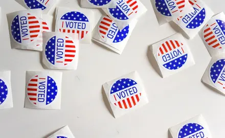 Stickers reading "I voted" are scattered on a white surface.