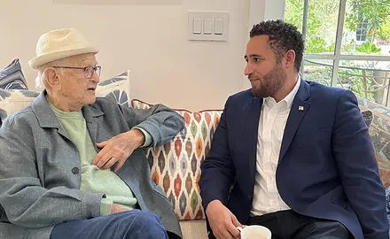 Norman Lear and Svante Myrick sit next to each other on a sofa discussing antisemitism.