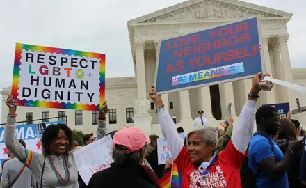 Protestors hold signs supporting LGBTQ rights outside the Supreme Court Building.