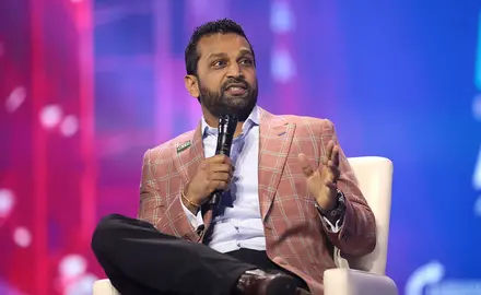 A photo of Kash Patel wearing a pink jacket and holding a microphone.