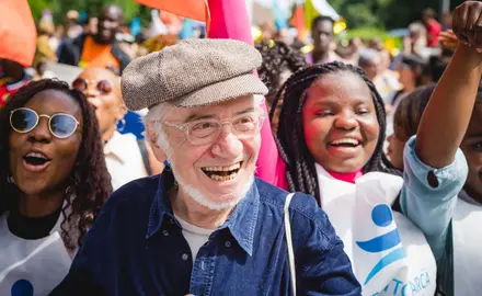 A grandparent smiling at a rally with younger people.