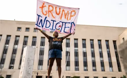 A protester displays a sign outside of the E. Barrett Prettyman U.S. District Court House in Washington, D.C., on Tuesday, Aug. 1, 2023. Members of a grand Jury met to examine former President Donald Trump’s role in the Jan. 6 riot and effort to overturn the 2020 election.