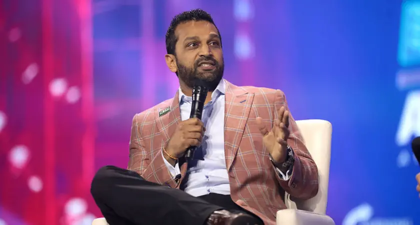 A photo of Kash Patel wearing a pink jacket and holding a microphone.