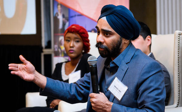 A man in a turban and suit speaking into a microphone
