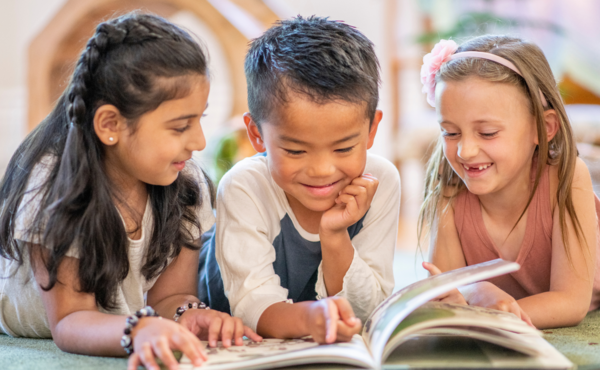 Three kids reading a book