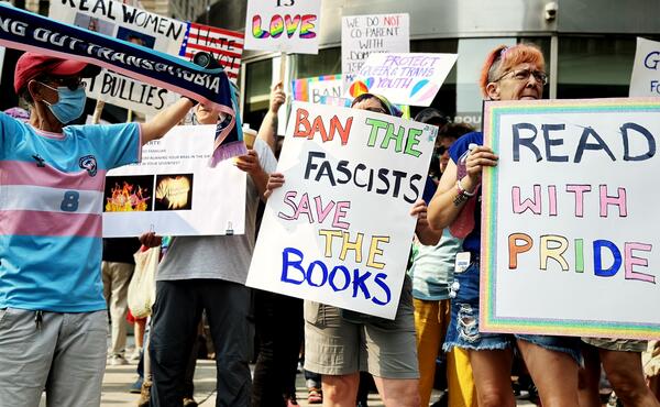 A group of protesters hold signs that say "read with pride" and "ban fascists, save the books"