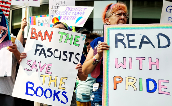 Protesters hold signs that read "ban the fascists, save the books," and "read with pride" 