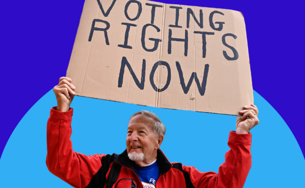 A man holds a sign that reads "voting rights now" against a blue background