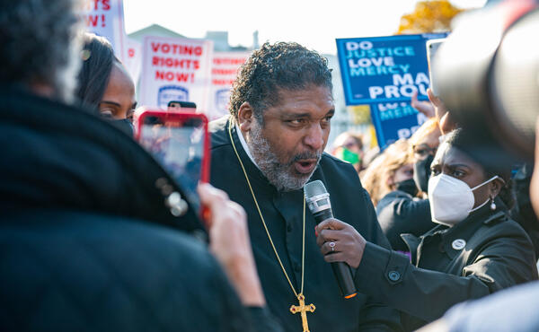 Black faith leader speaking into a microphone