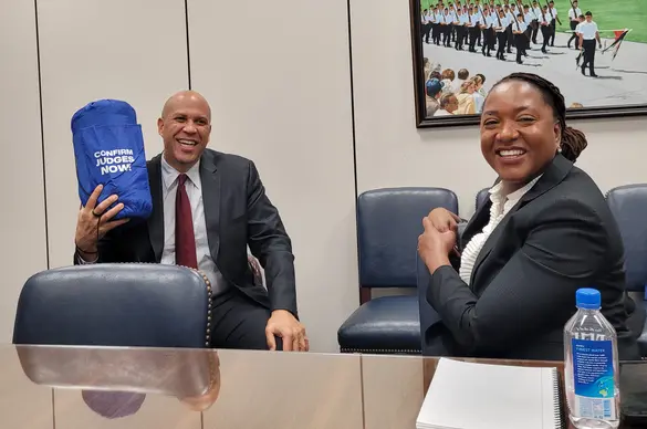 senator Cory Booker holds a sleeping bag that reads "confirm judges now"